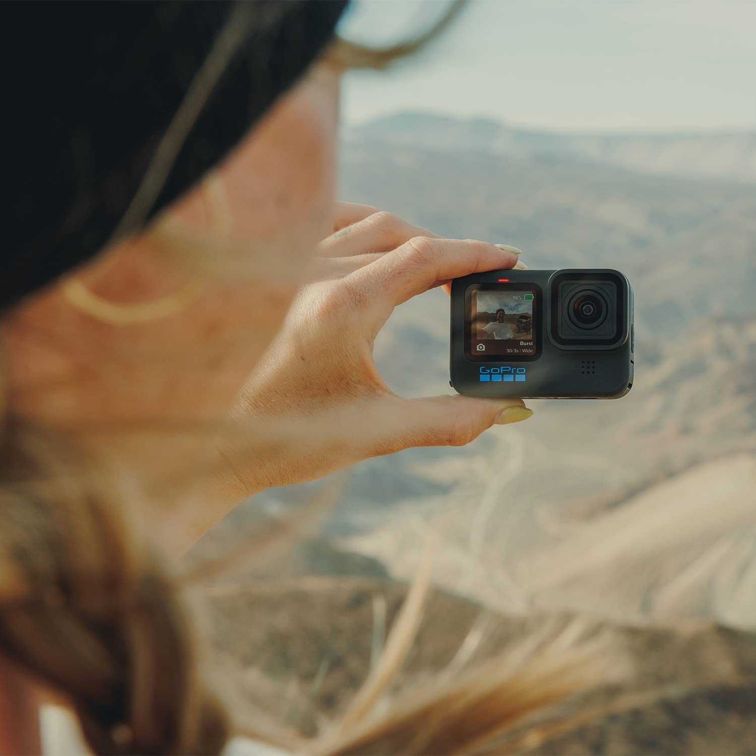 Woman holding a GoPro Hero 11 up to a beautiful view 
