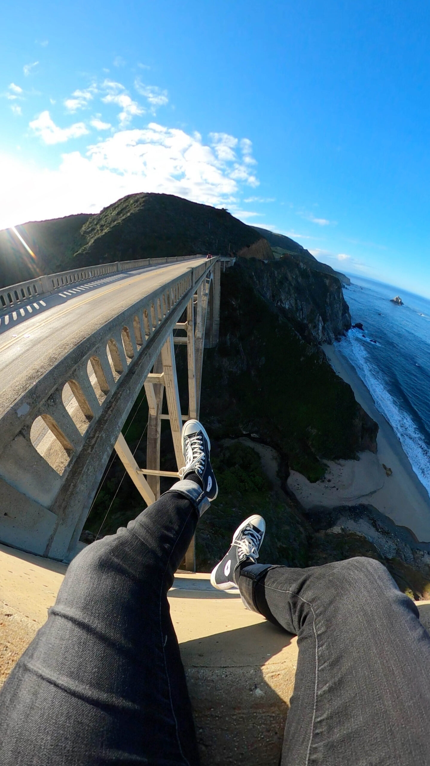 Man on a ledge in big sur taking a wide angle photo