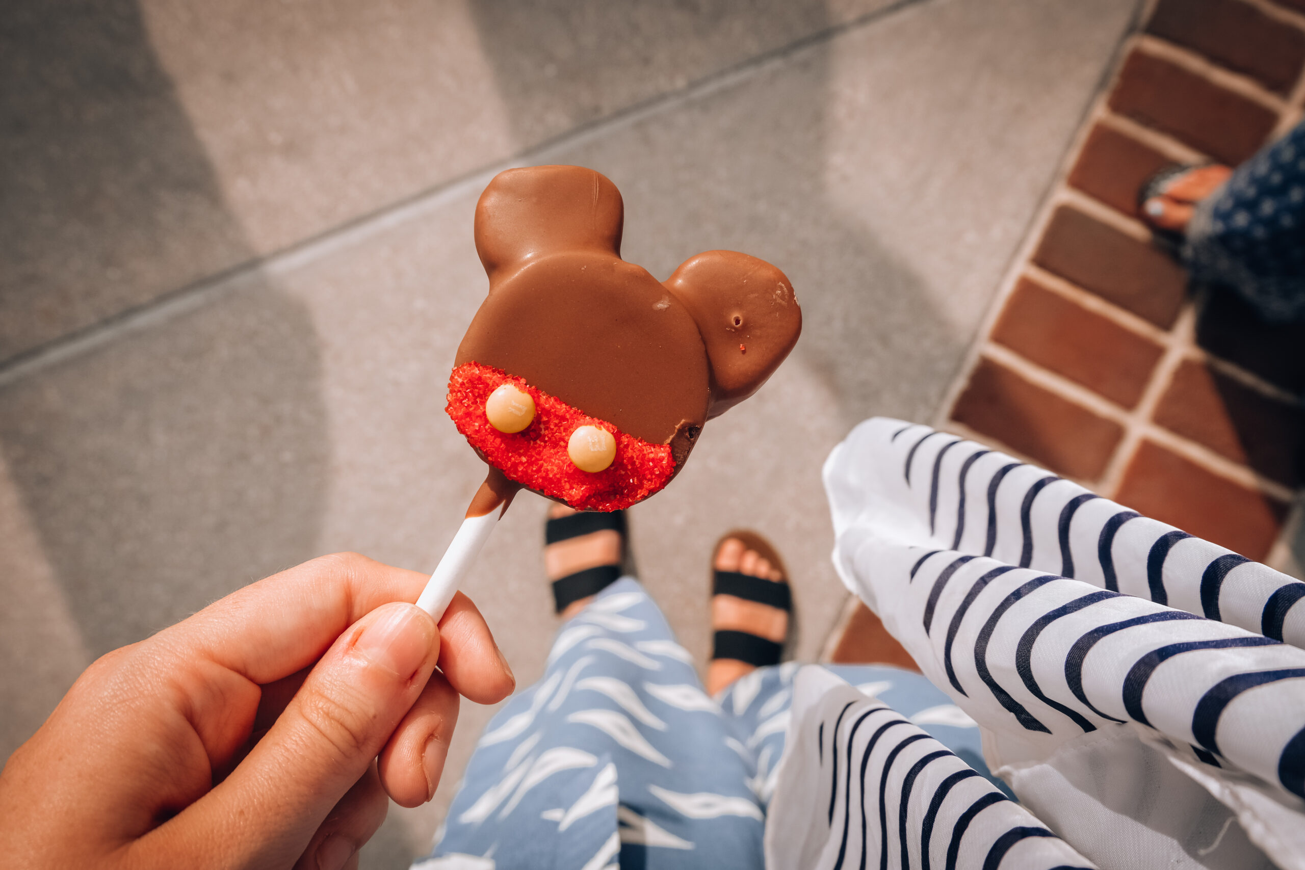 Holding a mickey mouse shaped cake pop